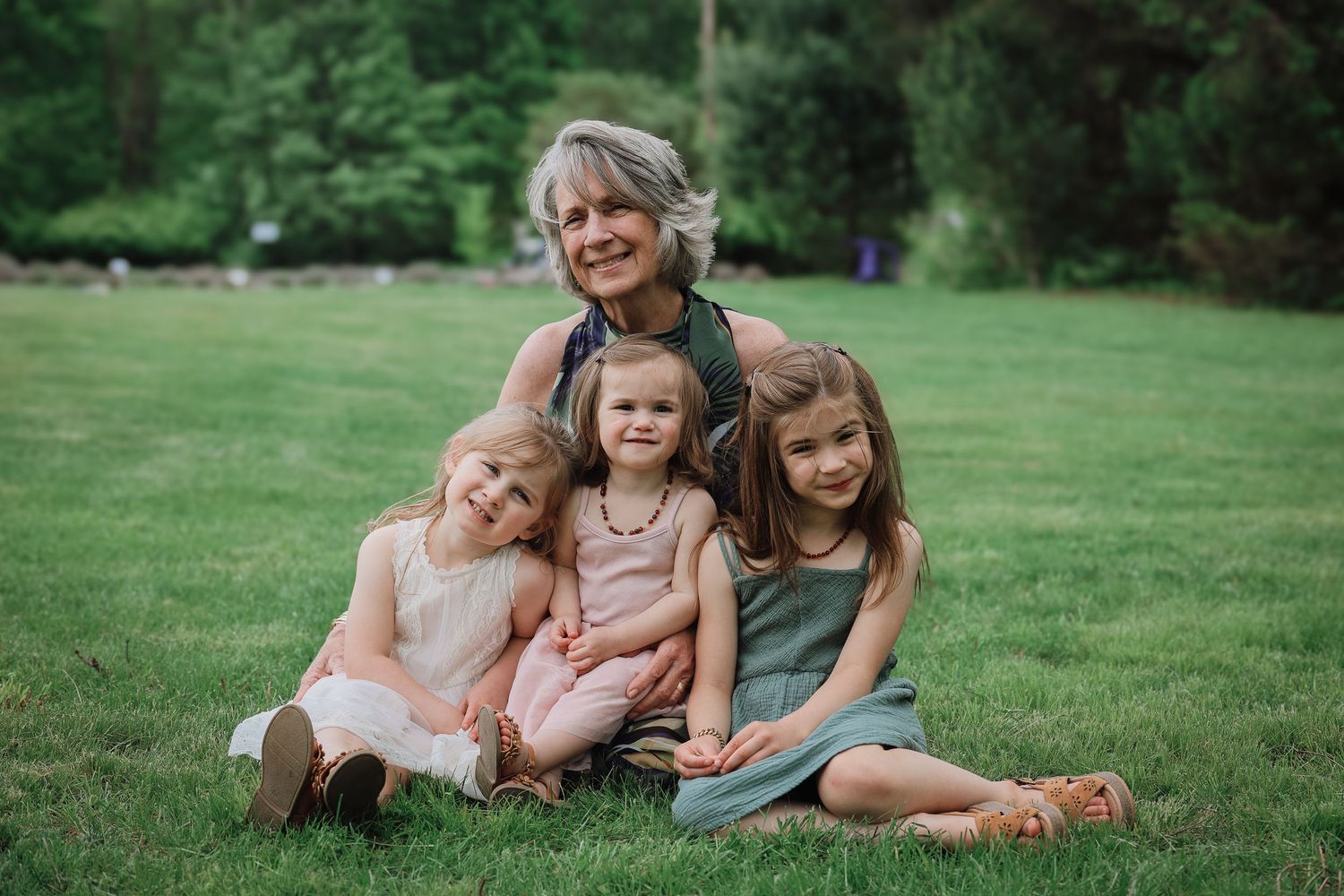 Family relaxing together on lush green grass during an outdoor photo session.