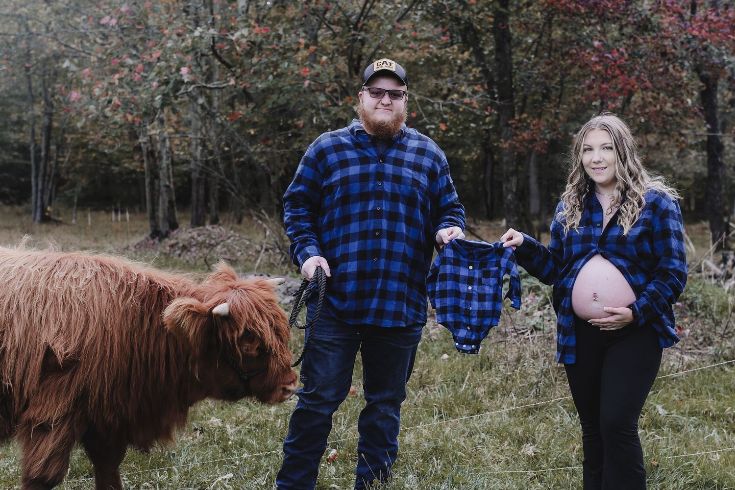 A family stands together in a field with a brown Highland cow during an outdoor photo session.