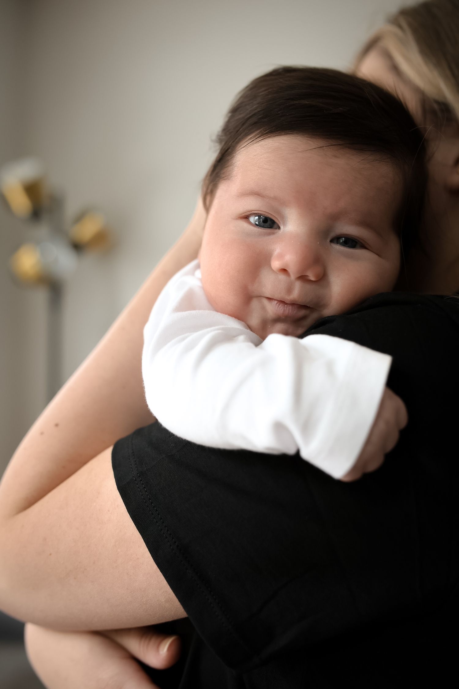 Close-up portrait of baby wearing white bow against dark background.