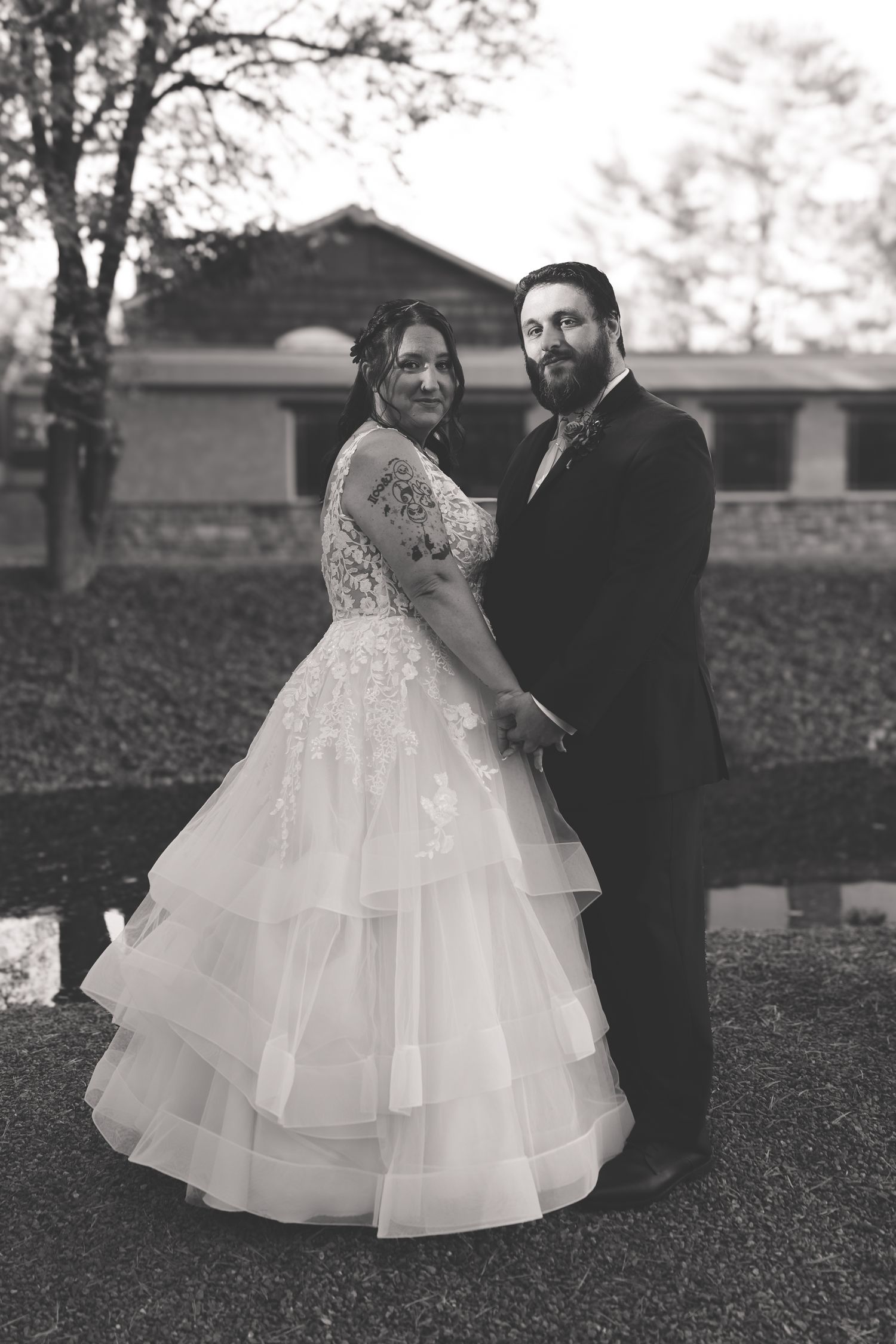 A couple shares an intimate moment in a garden setting with the bride wearing a layered ballgown wedding dress.