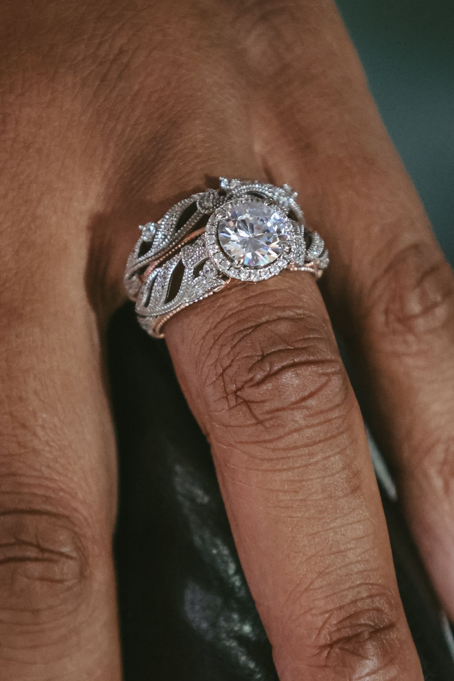 Close-up view of a sparkling diamond engagement ring with intricate filigree details on a silver band.