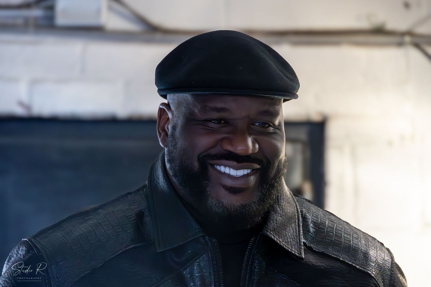 A person in a black hat smiles warmly while sitting in what appears to be a vehicle.