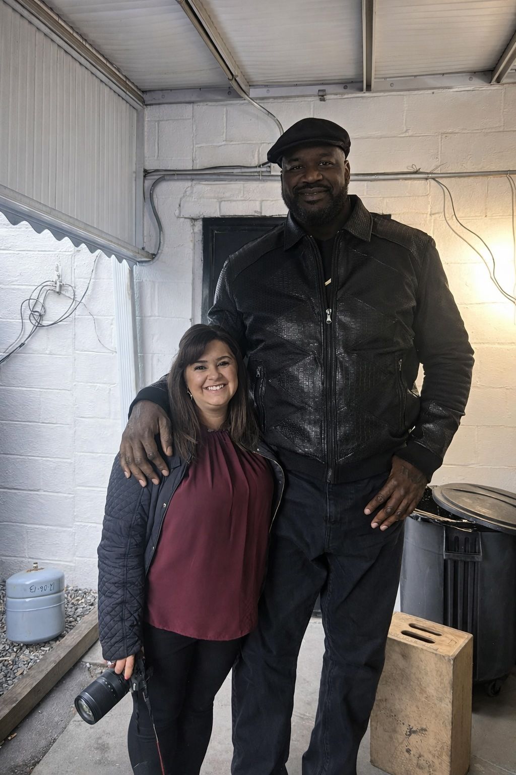 Two people posing together in casual attire inside industrial-style room.