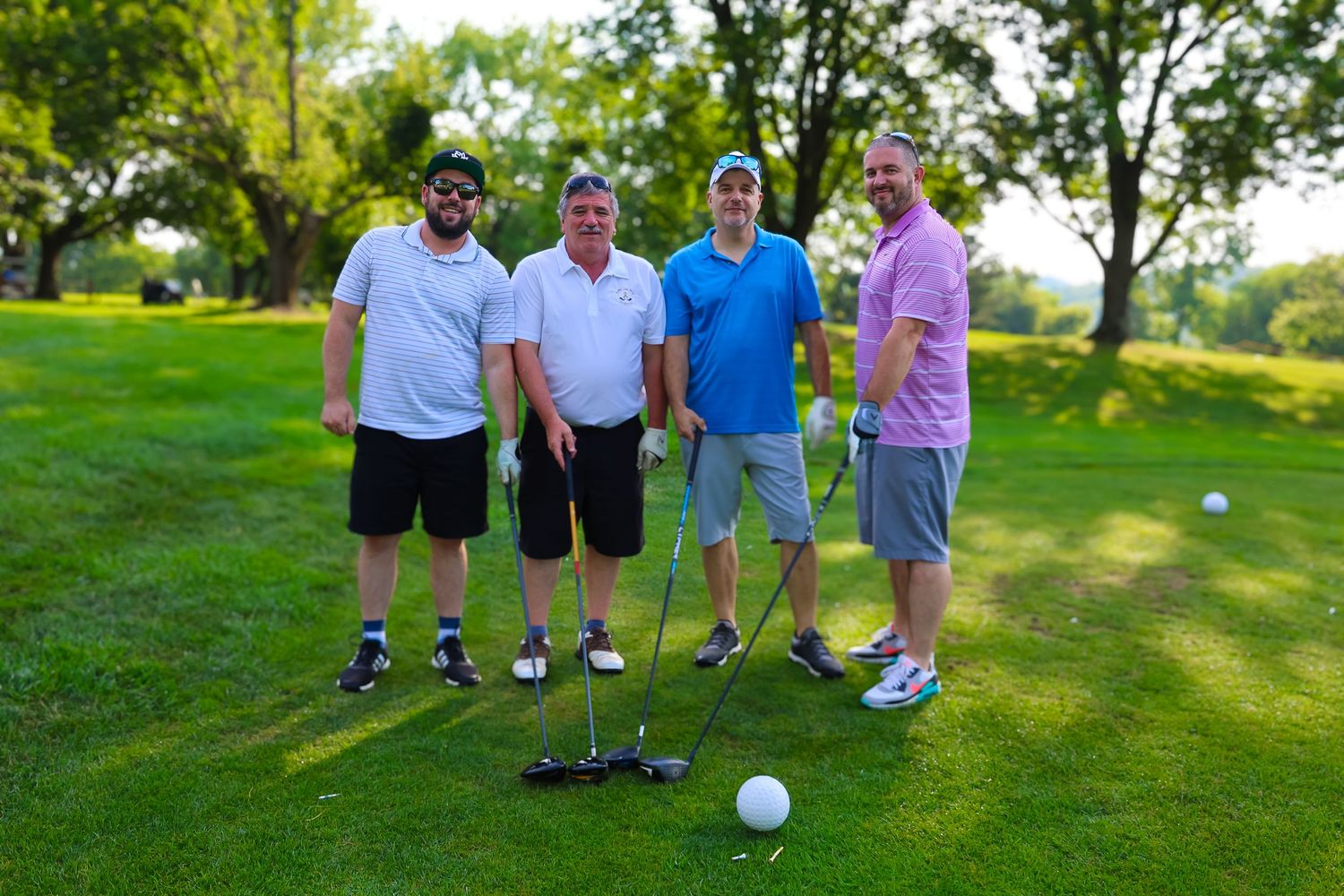 Group of golfers standing together on a lush green course during a sunny afternoon.