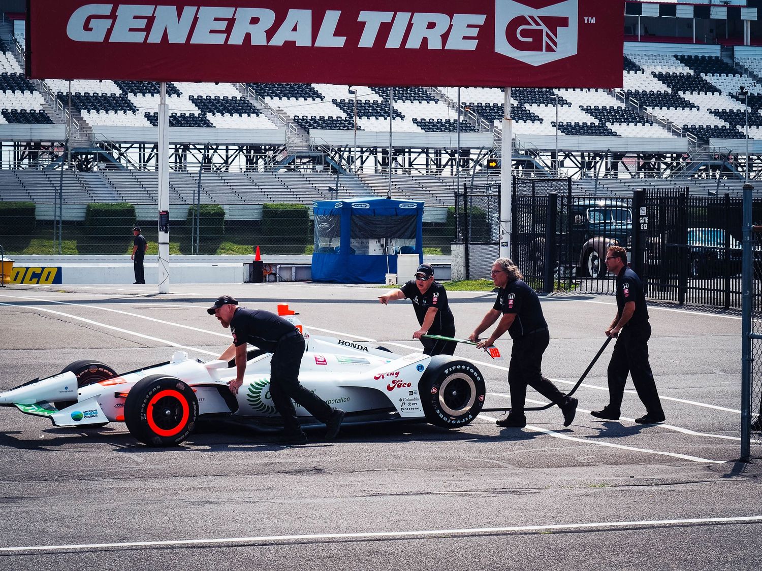 Pit crew members service an IndyCar race car during a pit stop at a General Tire sponsored racing event.
