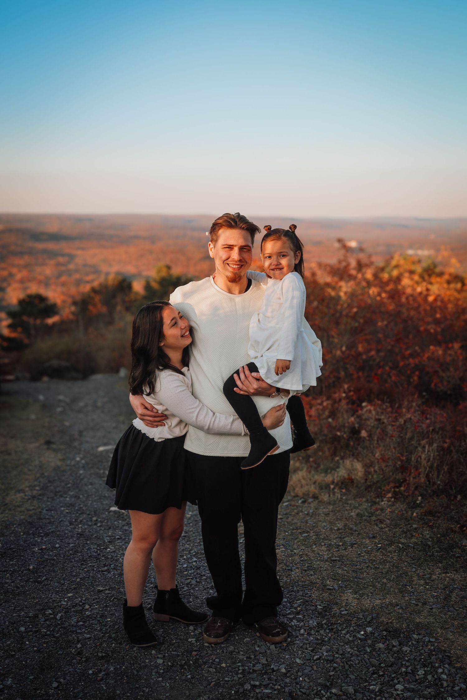 A group shares a tender moment together while enjoying sunset views from a hilltop overlook.