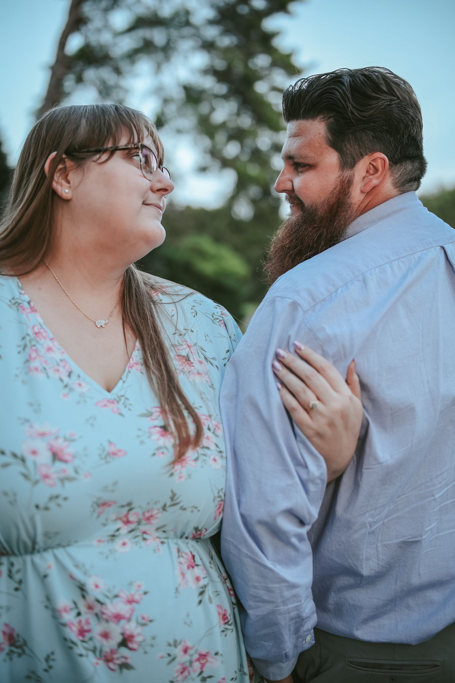 A couple in floral dress and blue shirt share tender romantic moments in a series of outdoor engagement photos.
