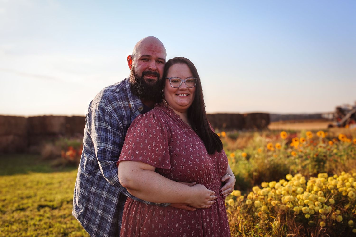 A couple embraces in a golden sunflower field during sunset creating a romantic outdoor portrait.