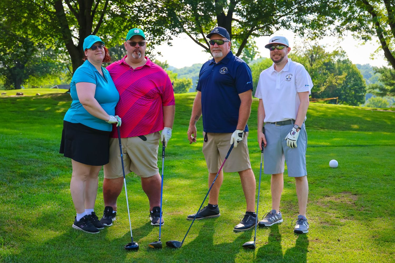 A group of golfers stand together on a lush green golf course during a sunny day.
