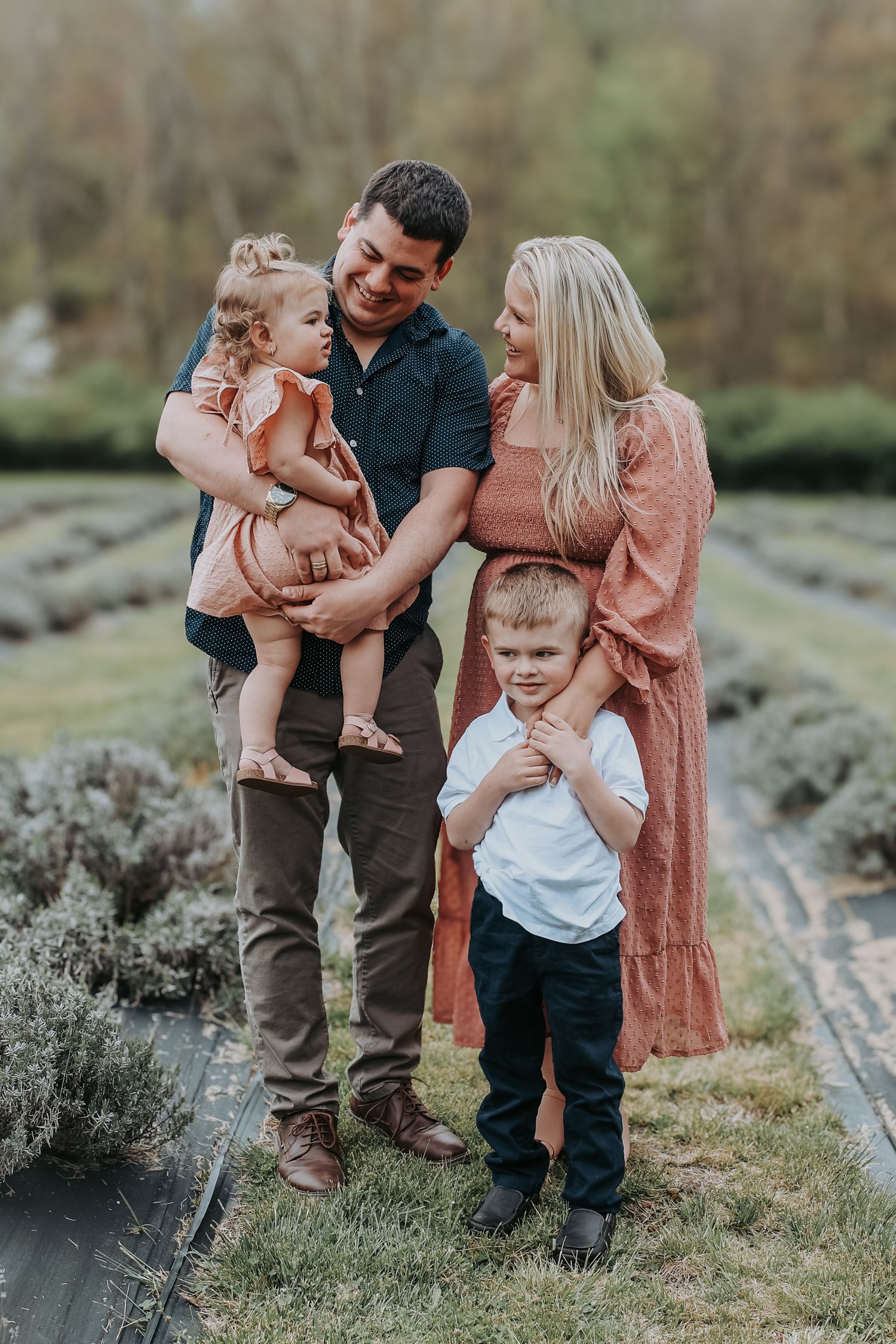 A loving family shares playful moments together outdoors on a grassy hill during a casual photo session.