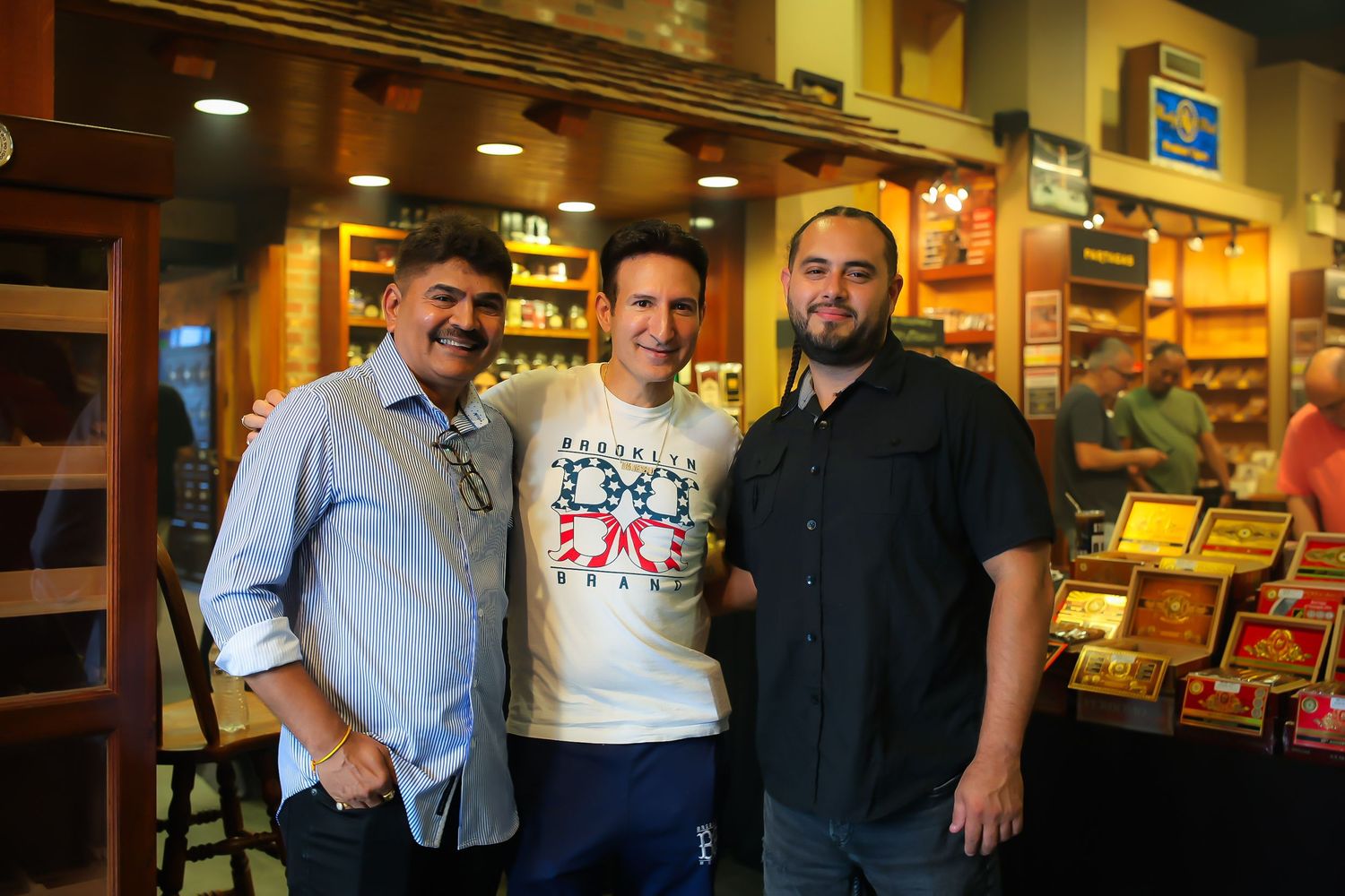 Customers and staff pose together inside a restaurant with warm lighting and casual dining atmosphere.