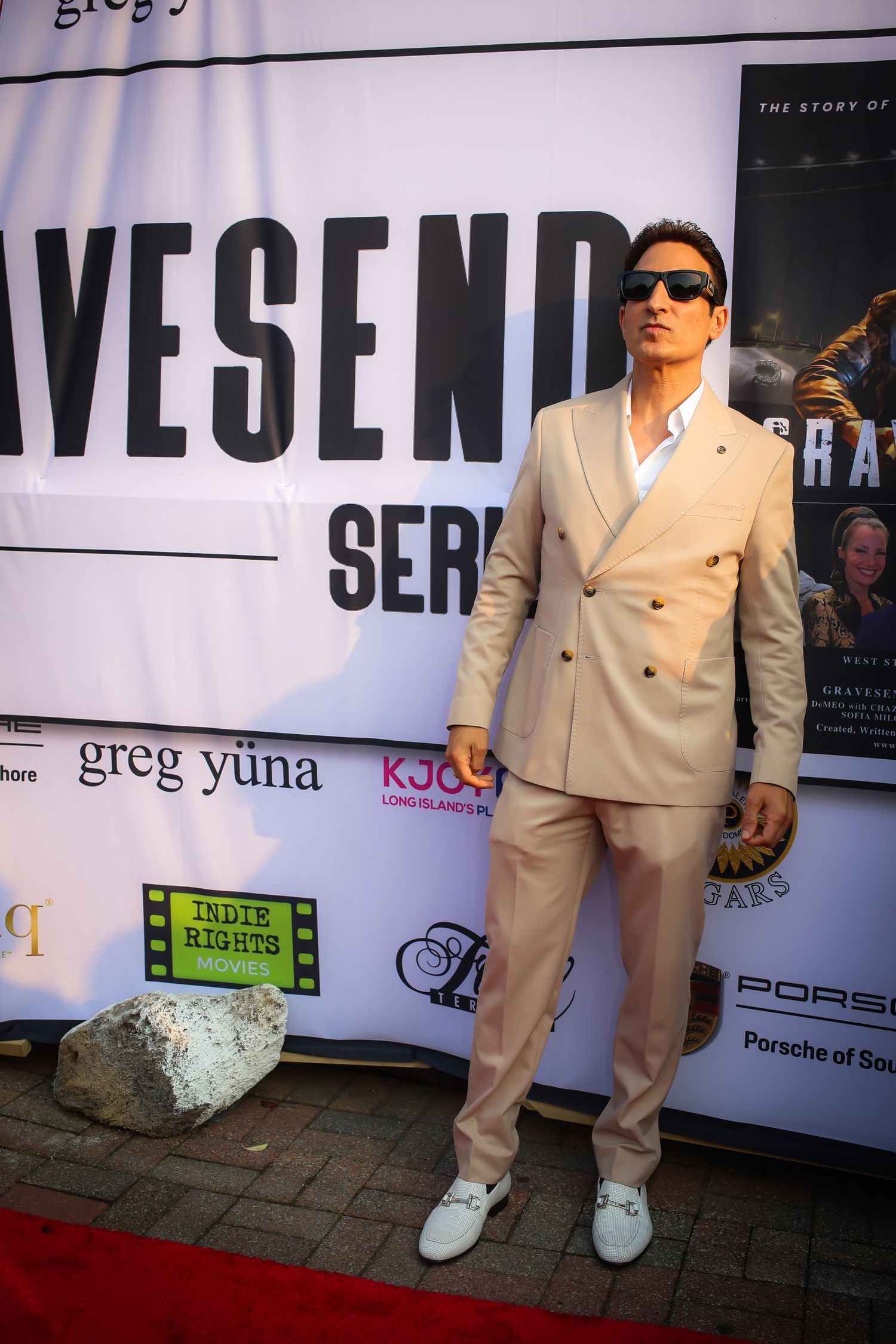 A series of connected photos showing someone in a cream-colored suit and white sneakers posing against a branded backdrop.