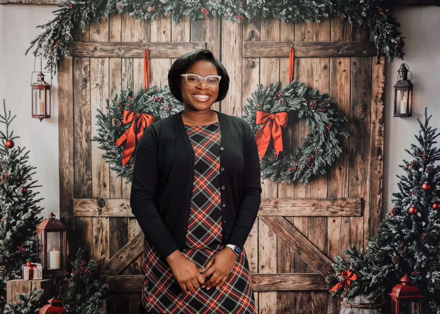 Holiday portraits in a rustic wooden barn setting with Christmas wreaths and festive decorations.