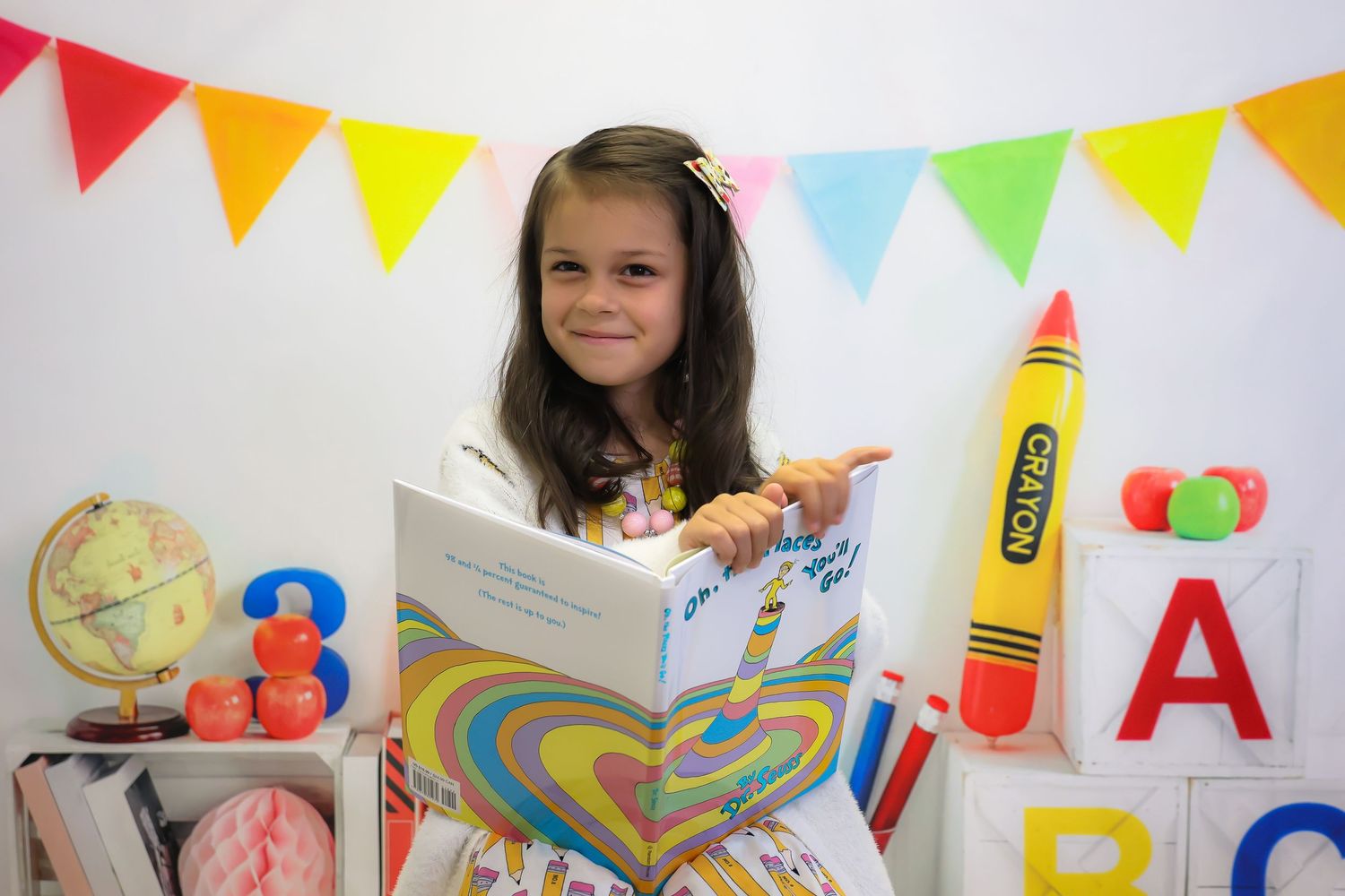 Colorful classroom decorations including alphabet letters, globe, and bunting flags create a festive learning environment.