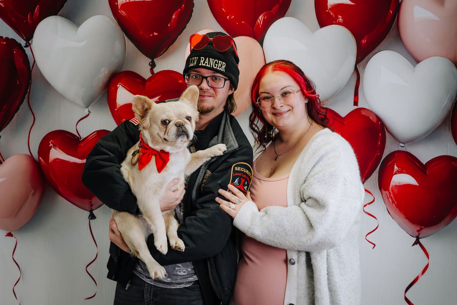 A romantic Valentine's Day photo session with heart balloons, white and red decor, and a small white dog.