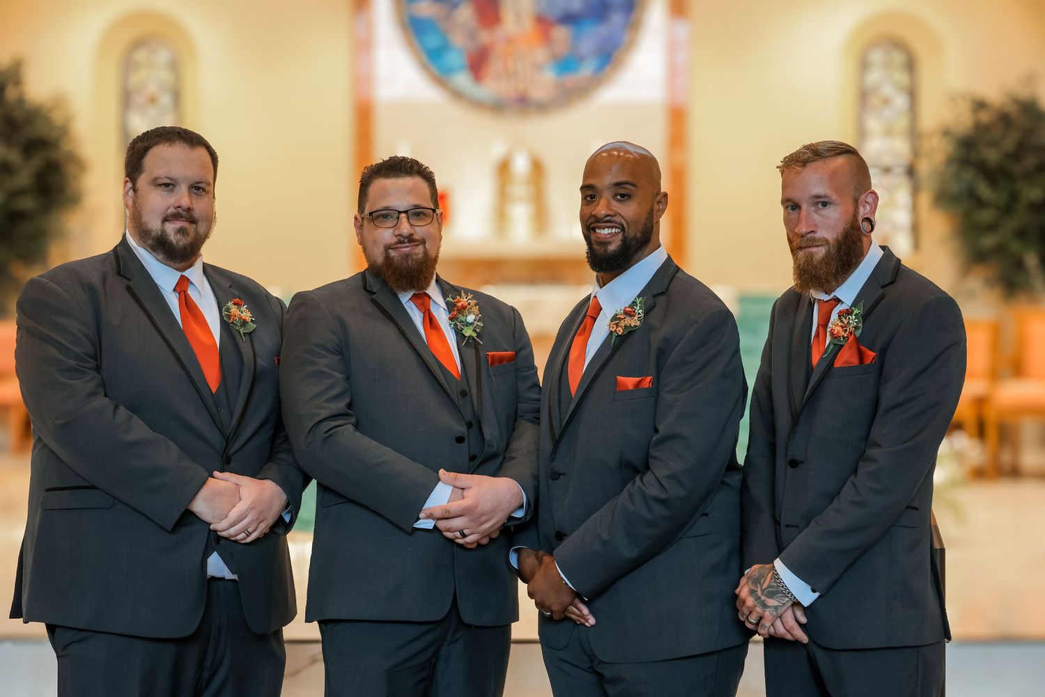 A group of people wearing dark suits with orange ties pose together in a formal setting.