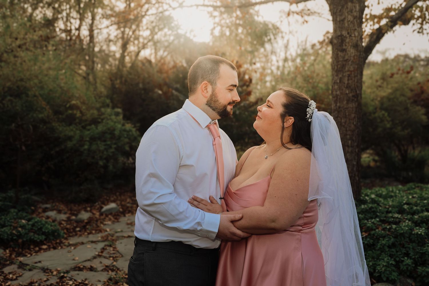 Romantic sunset photoshoot in a garden setting with soft golden light filtering through trees.