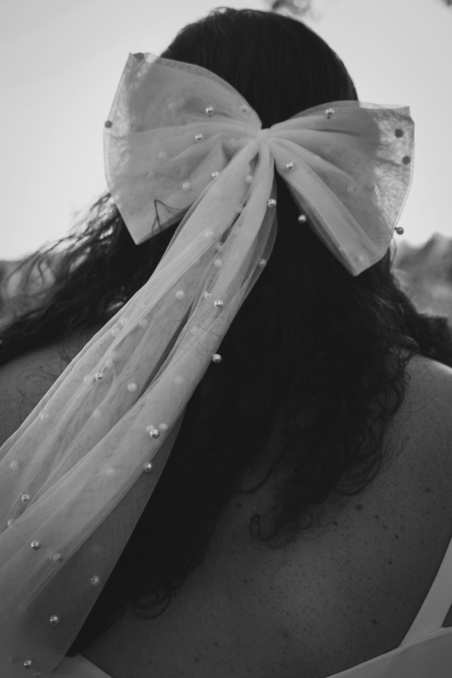 A series of black and white photographs showing a large decorative bow with rhinestone accents against a dark background.