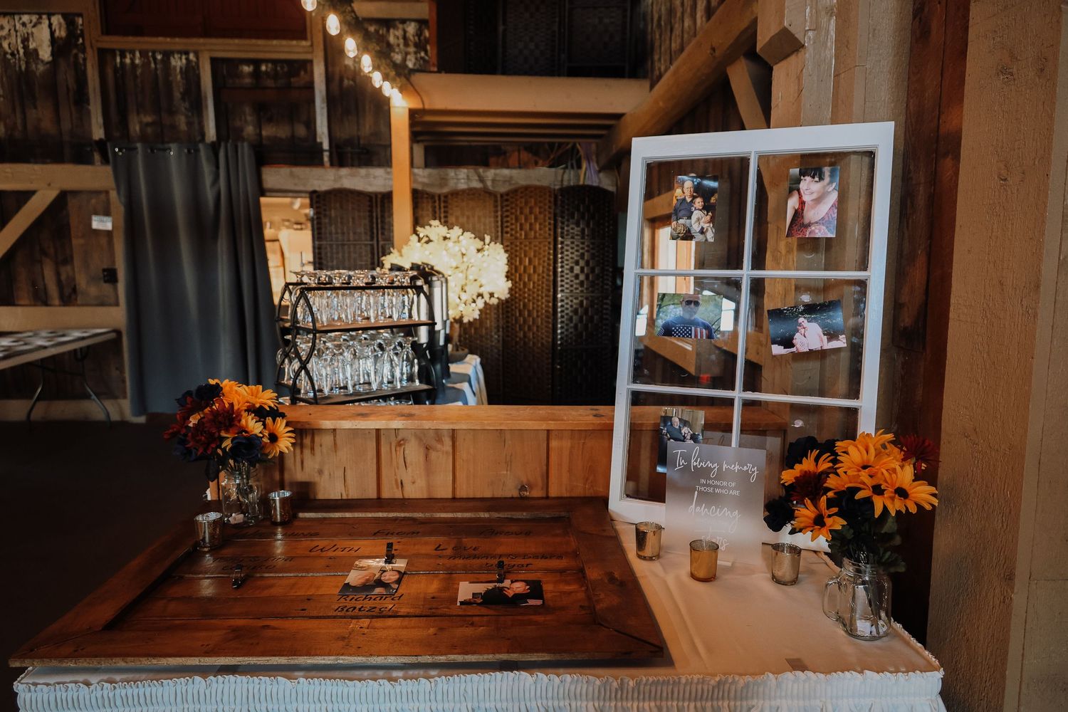 A rustic wooden table with vintage typewriter and orange floral arrangements in a barn-style setting.