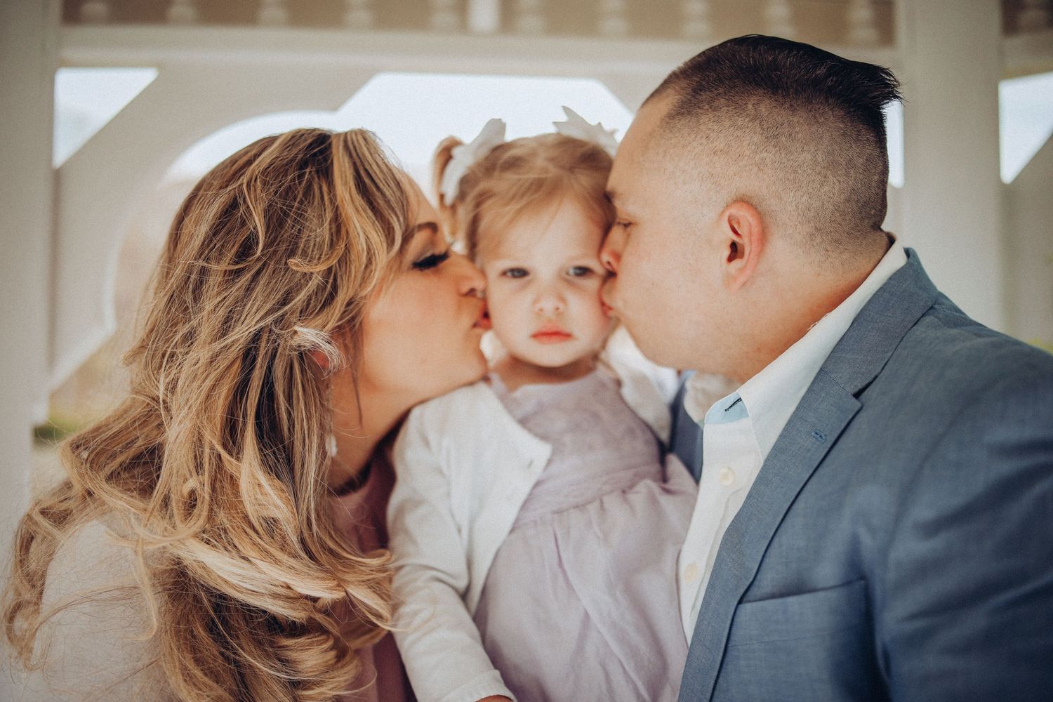 A family shares tender moments together in a series of intimate indoor portraits with soft natural lighting.