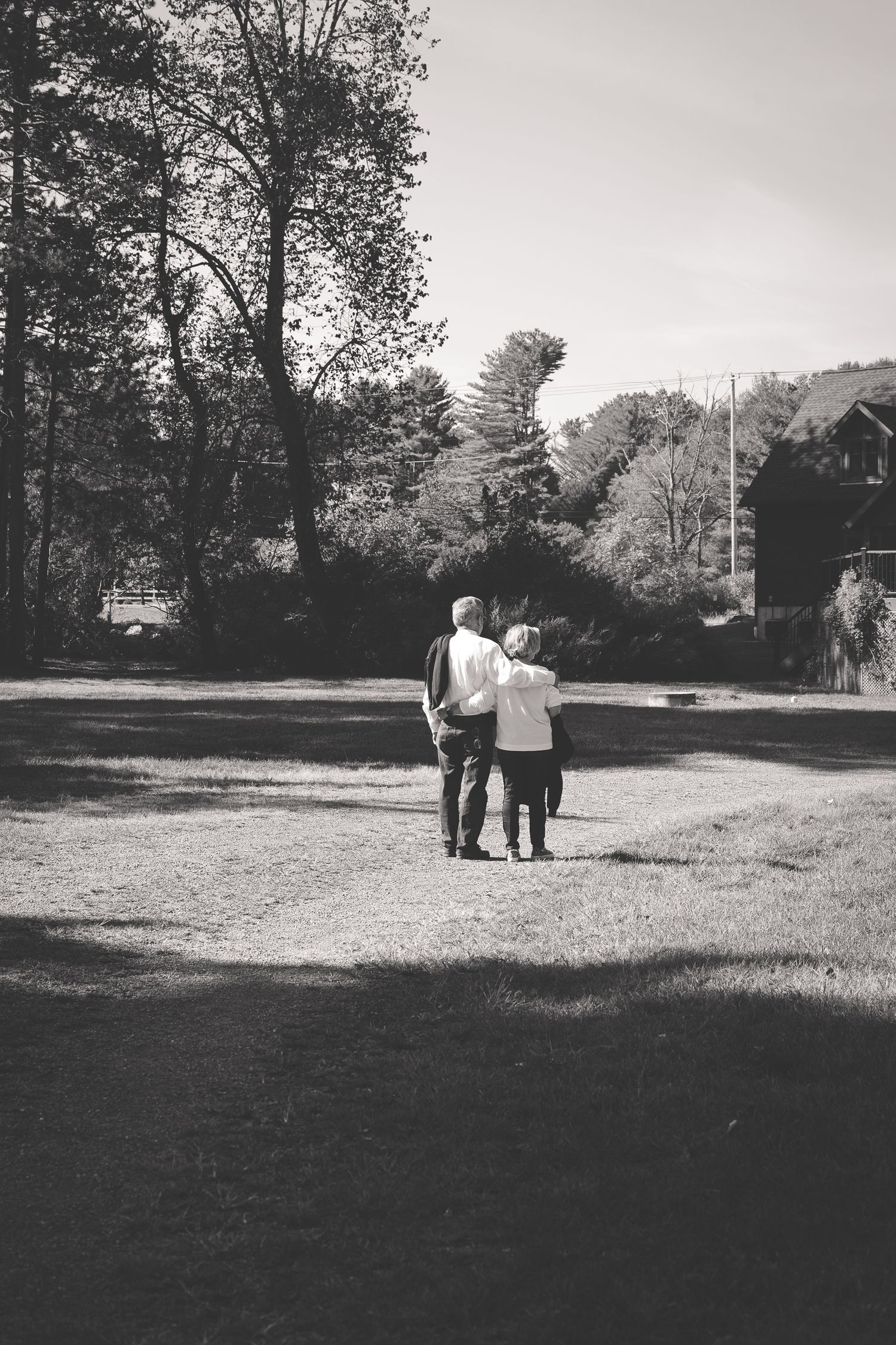 A sequence of black and white photos shows people walking across a grassy field on a sunny day.