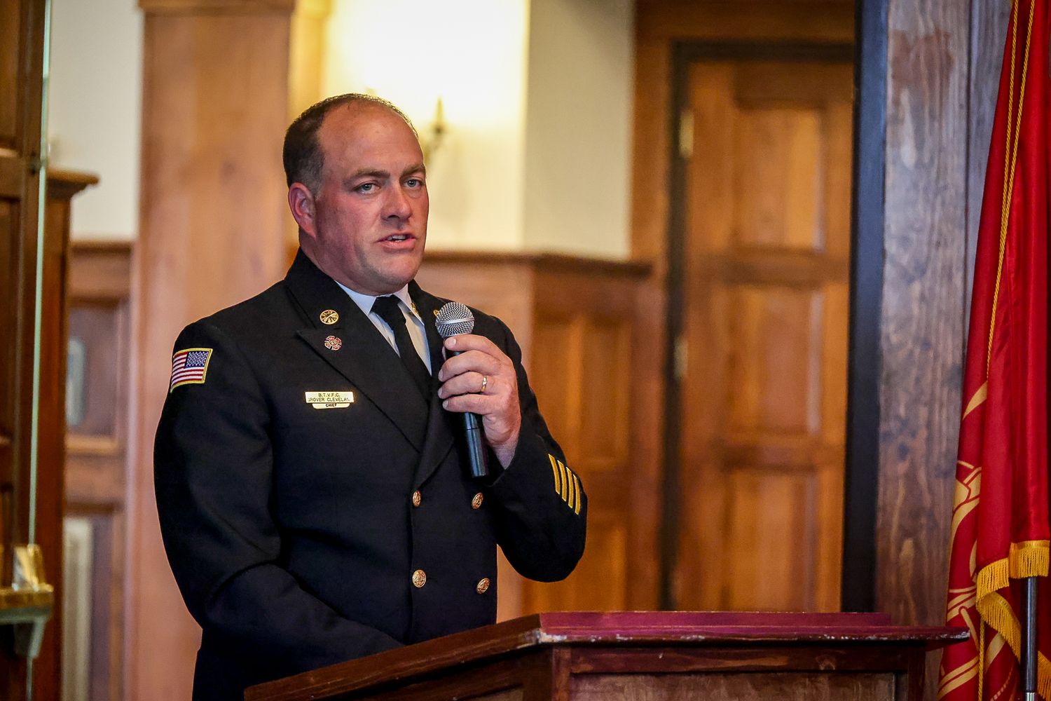 Military officer in dress uniform speaks at podium with microphone at formal ceremony.
