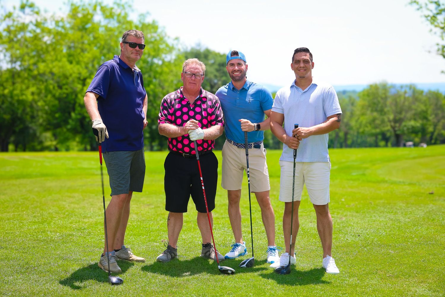 Golfers standing together on a lush green golf course on a sunny summer day.