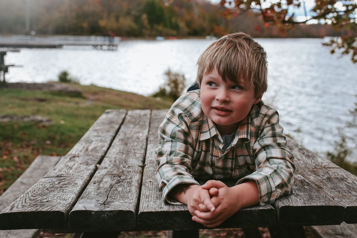 A sequence of outdoor photos showing someone resting on a wooden dock by a lake during autumn.