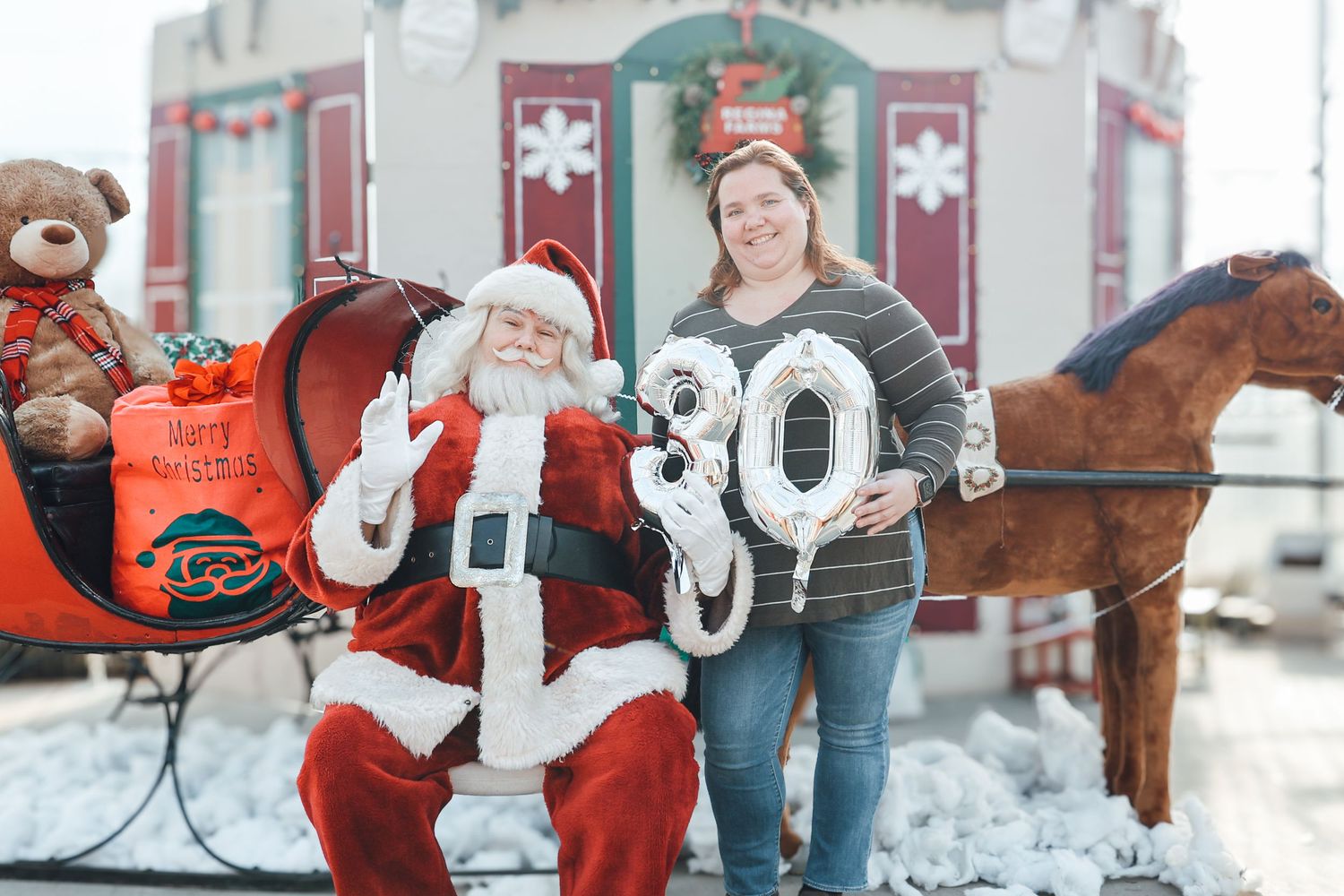 A festive holiday scene with Santa Claus and children playing in the snow during a winter photo session.