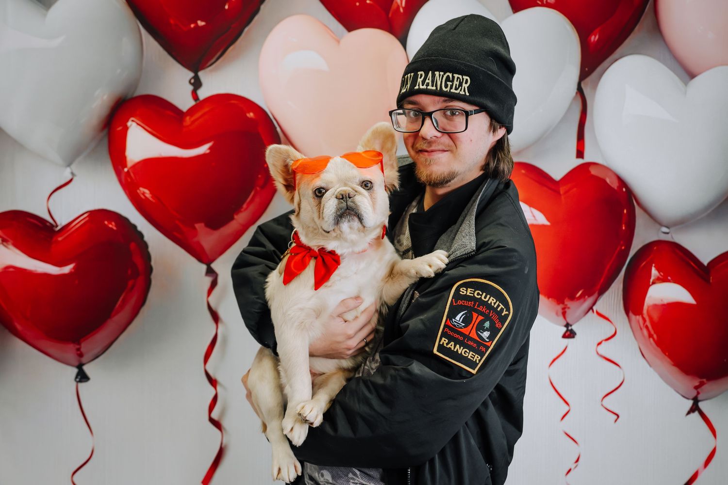 Red and white heart-shaped balloons create a romantic Valentine's Day backdrop for a cozy indoor photo session.