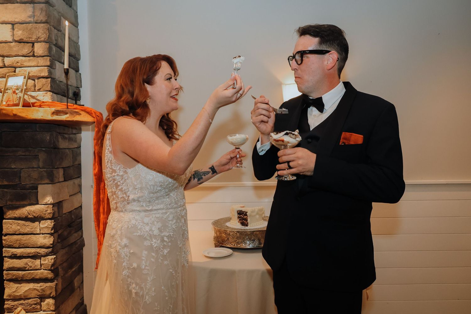 A couple shares a playful moment during their wedding reception while holding up sparklers indoors.
