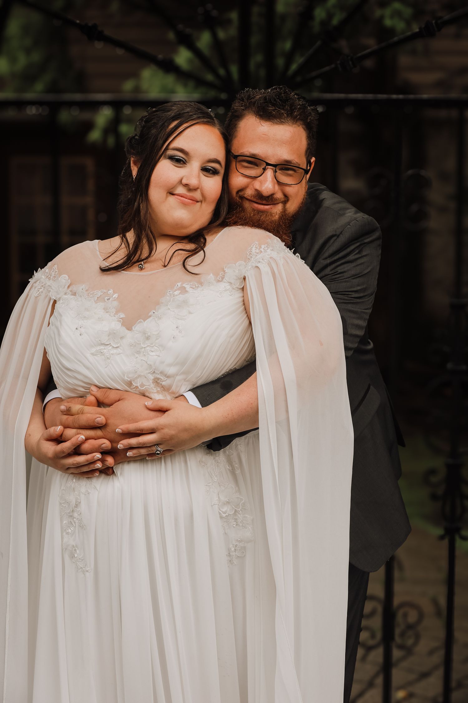 A couple in wedding attire embraces outdoors in a romantic photoshoot series.