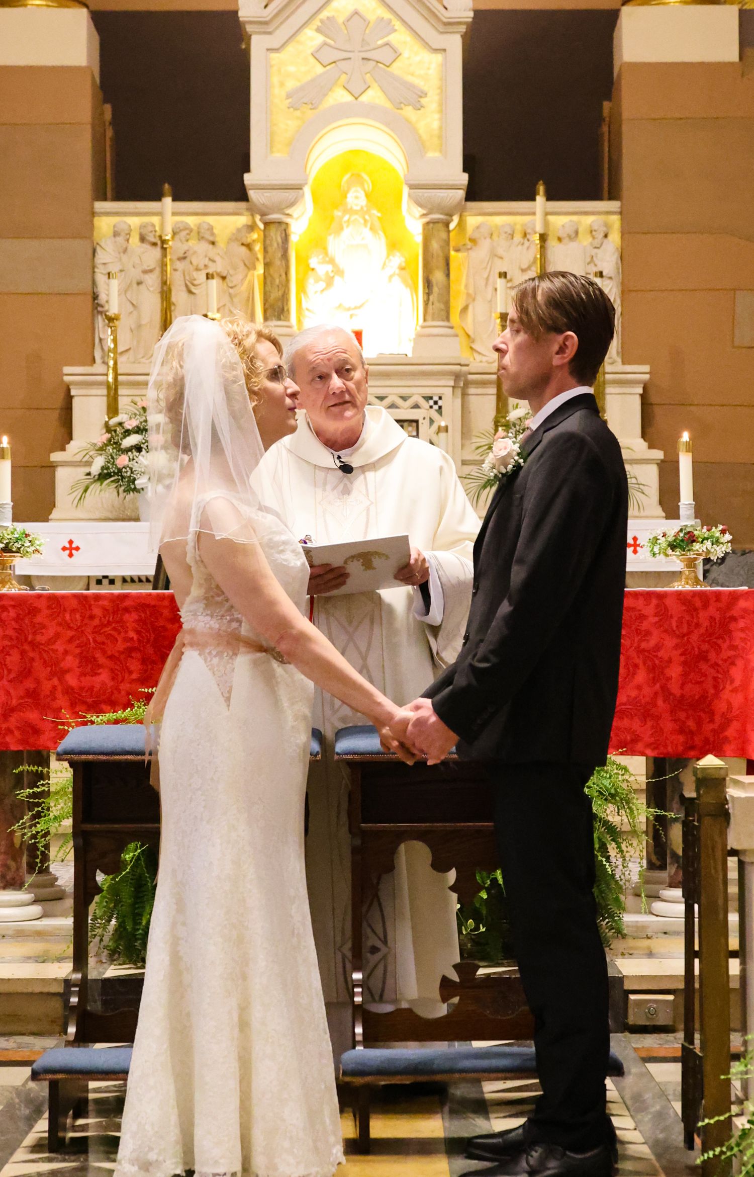 Wedding ceremony sequence shows couple exchanging vows at the altar in a church with red decor.