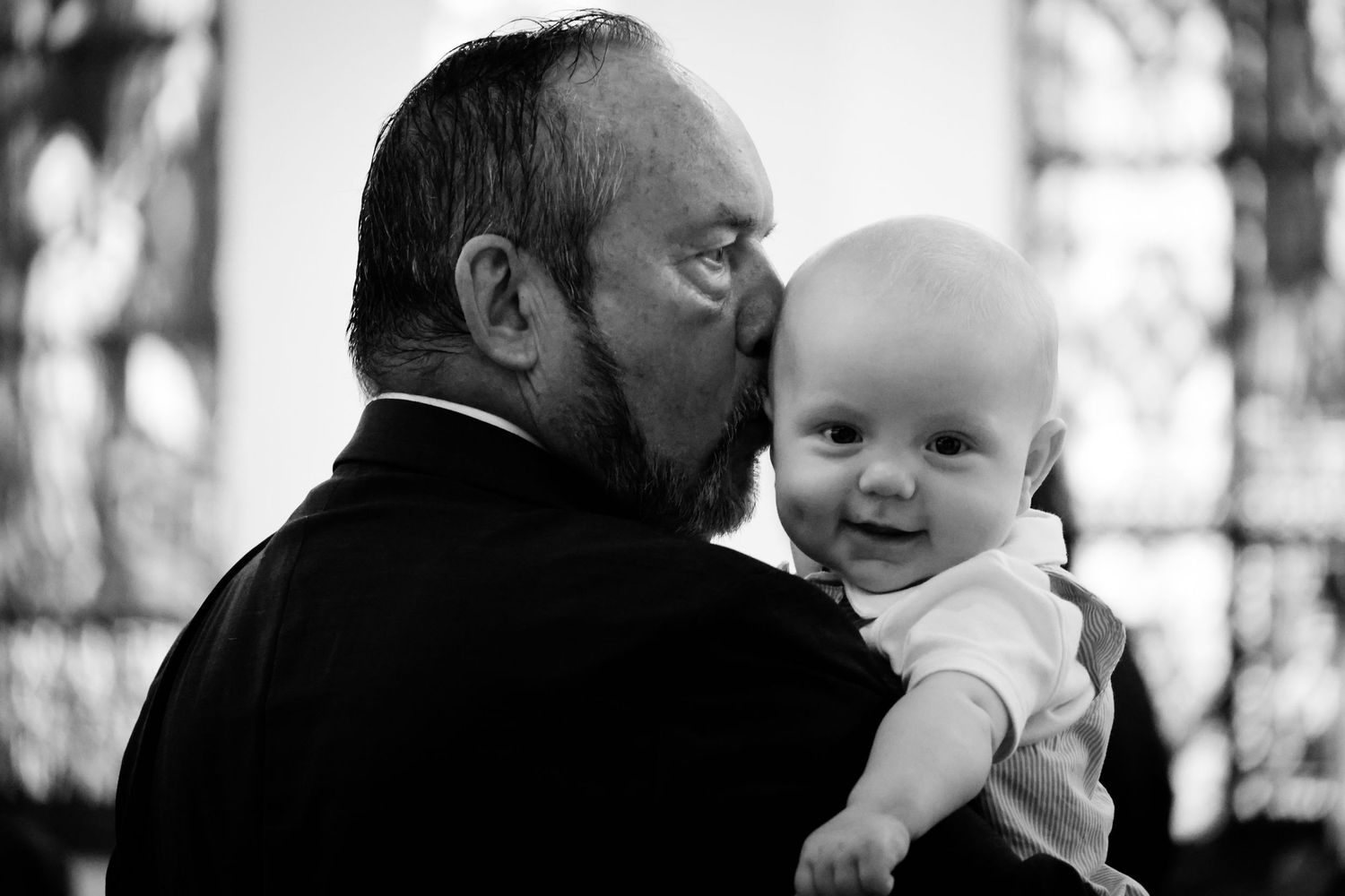 A series of black and white photos showing tender moments between an adult and baby in different candid poses.