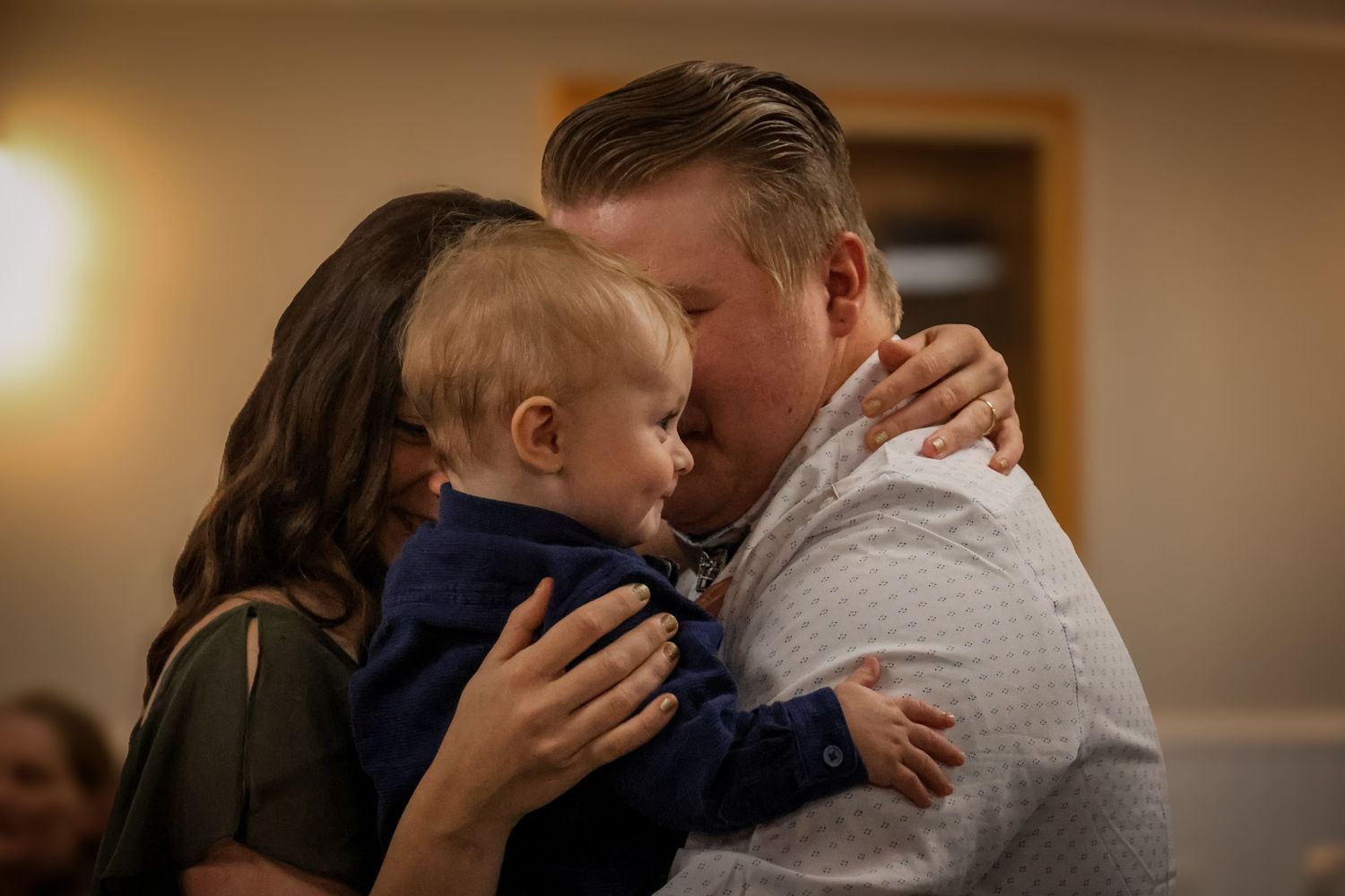 A tender moment is shared between parent and child in a warm, softly lit indoor setting.