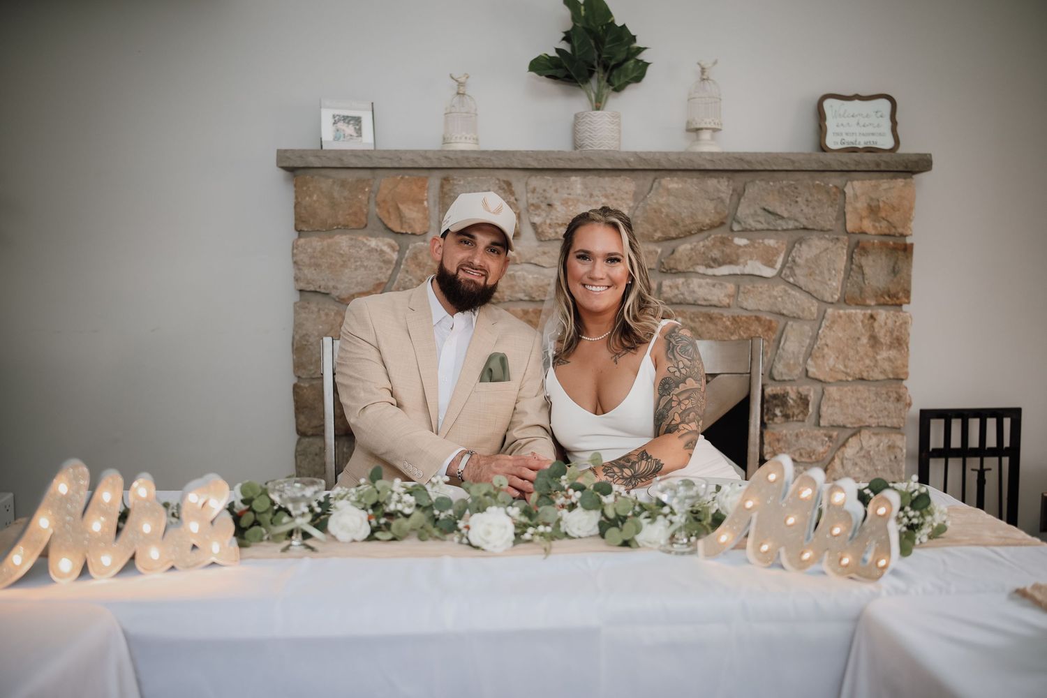A wedding reception venue with stone walls decorated with greenery and elegant white floral arrangements.