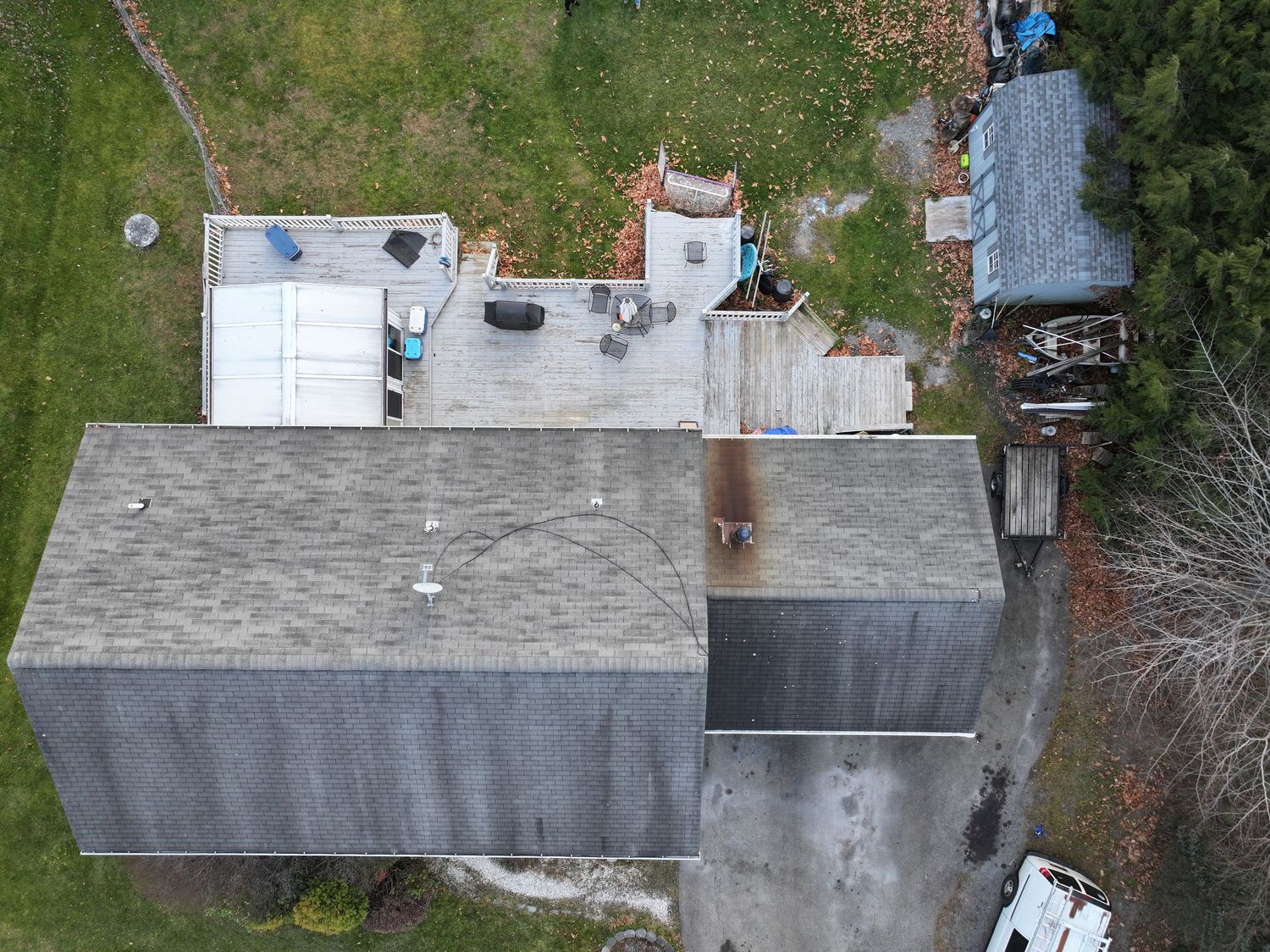 Aerial view of a residential roofing project showing shingle installation progress on a gray asphalt roof.