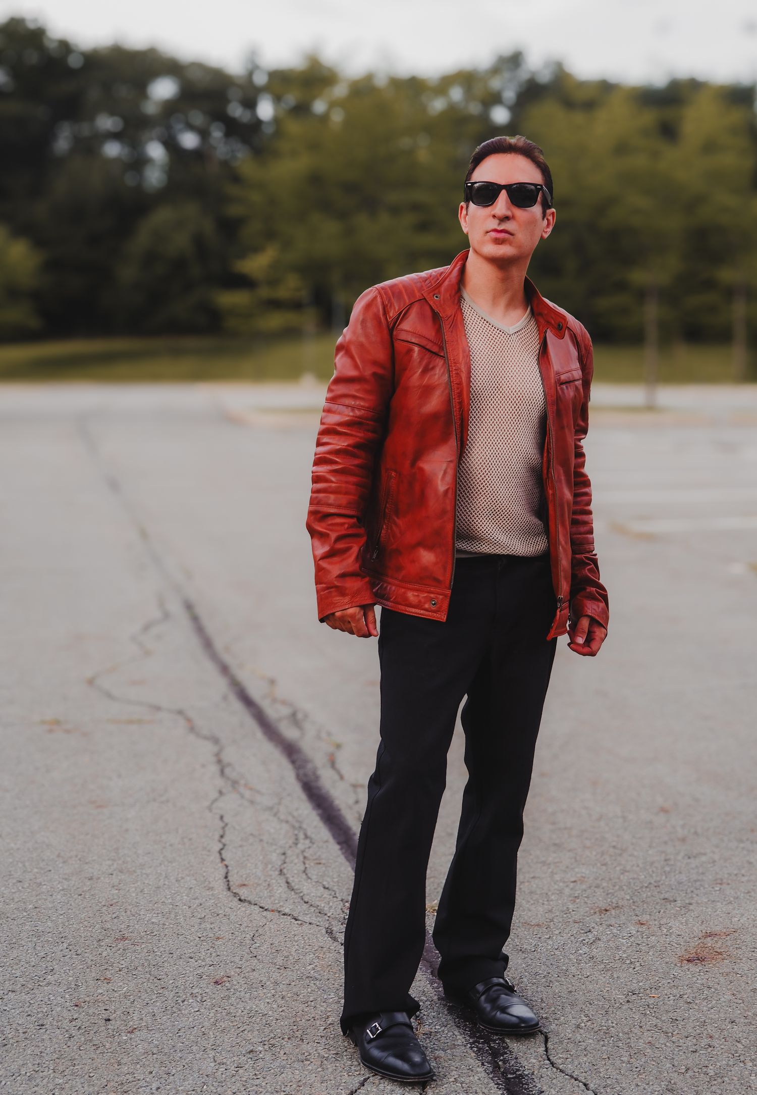 A person in a red leather jacket and black pants stands on a cracked concrete surface in a series of dynamic poses.