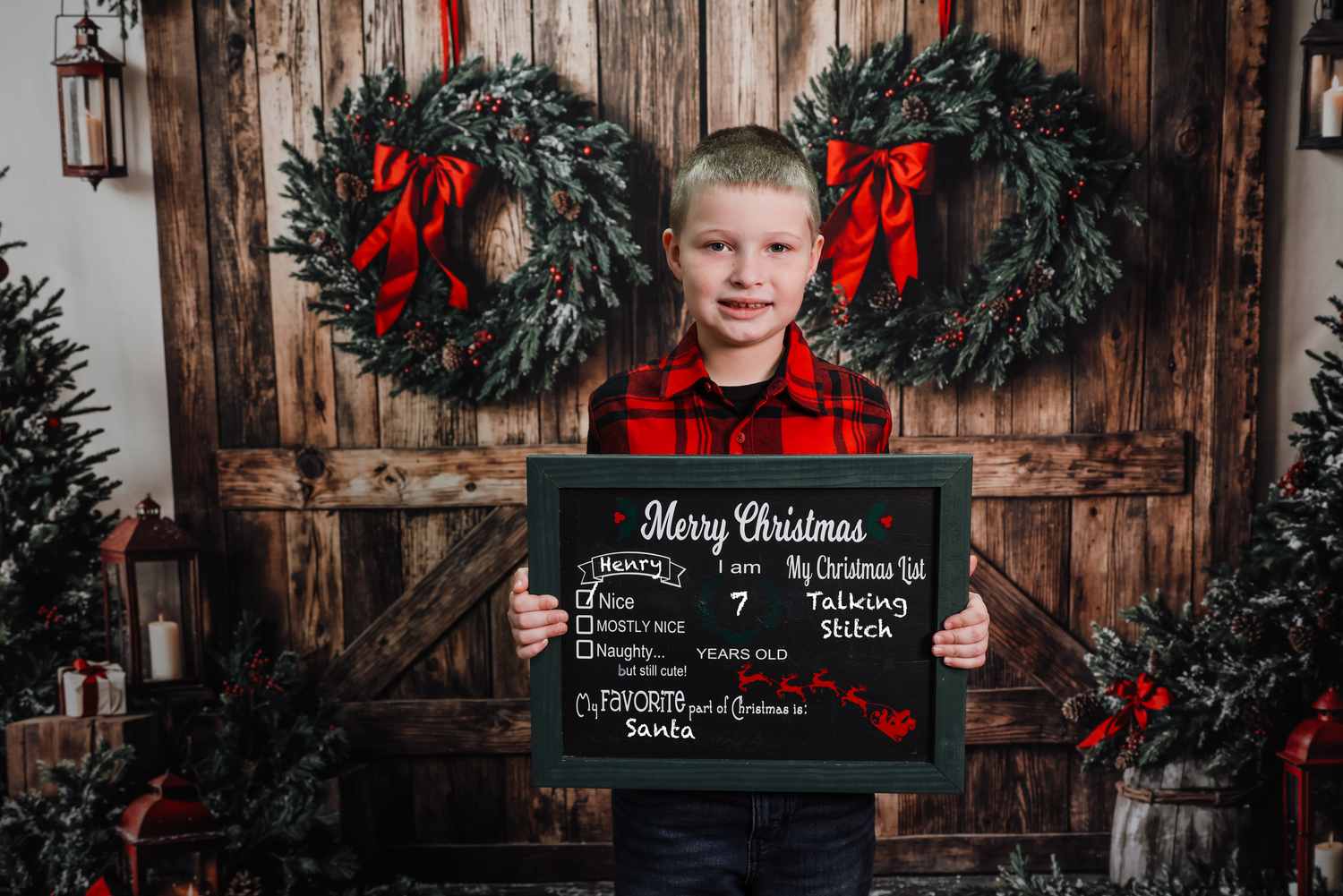 Holiday portrait with rustic wooden backdrop, evergreen wreaths with red bows, and chalkboard sign for Merry Christmas.