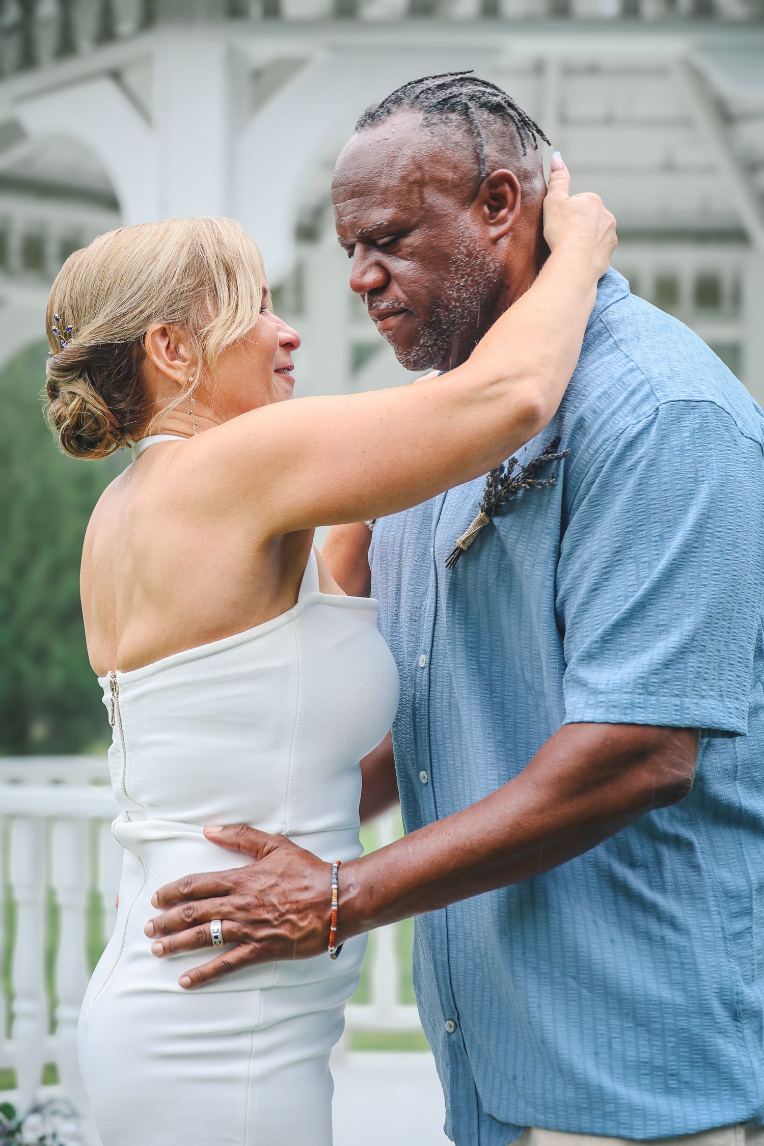 A couple dancing together outdoors in front of a white gazebo.