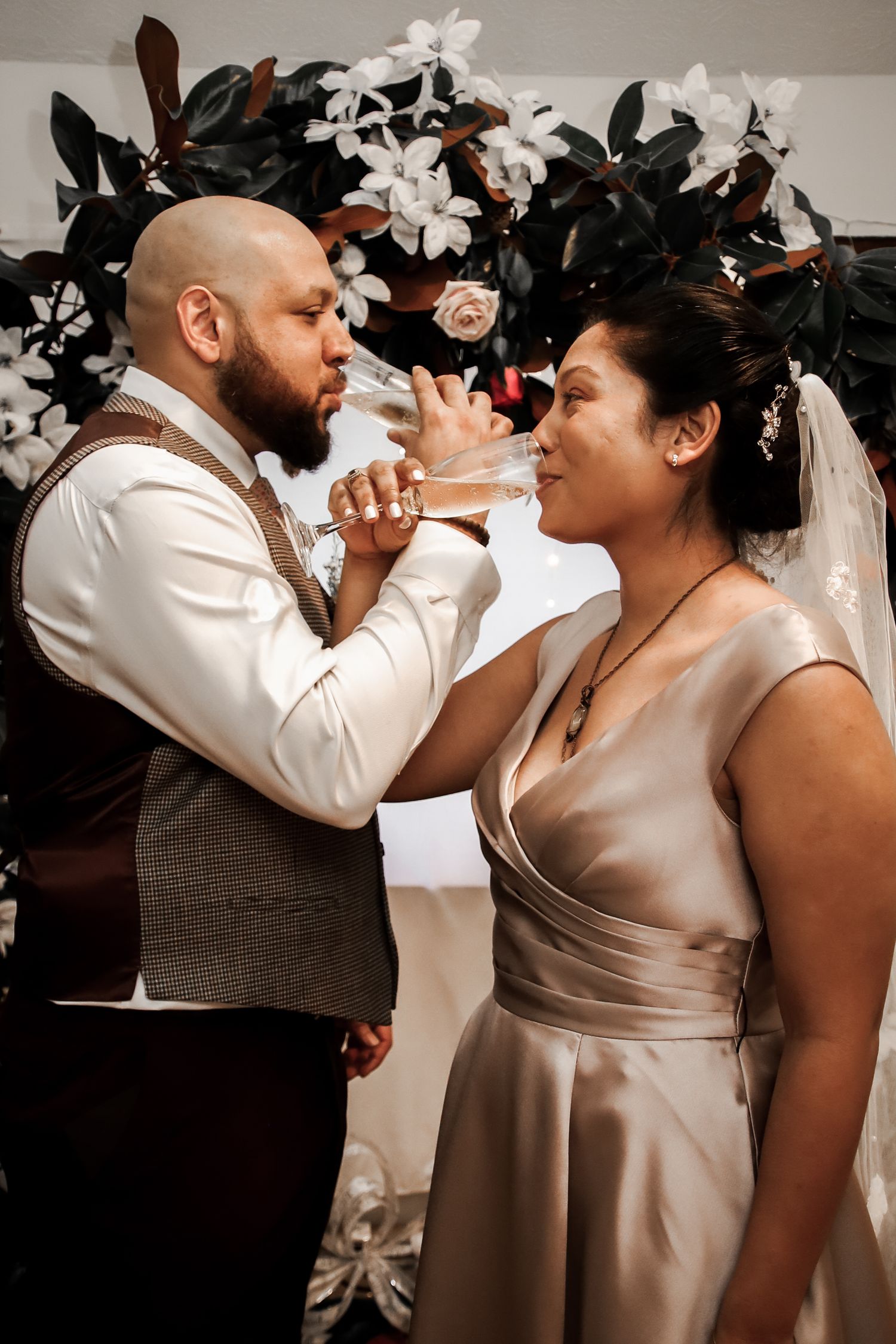 A romantic wedding couple shares an intimate dance moment in matching beige and white formal attire.