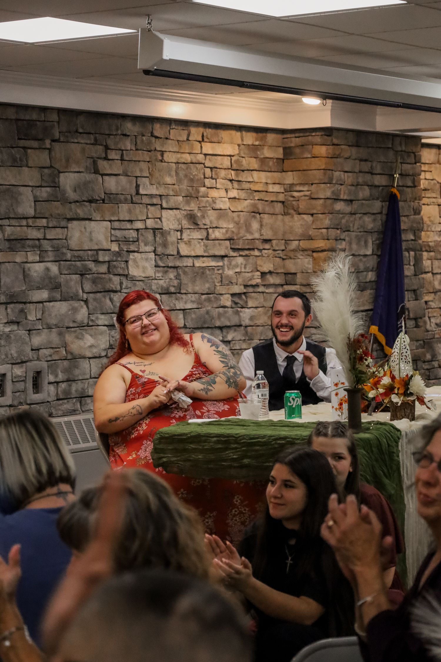 People gathered around a table for a social event in a room with stone walls and ambient lighting.
