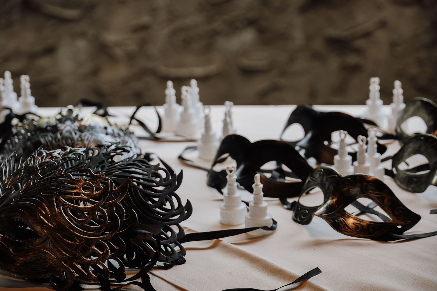 Black masquerade masks and decorative elements arranged on a white table for an elegant party setup.