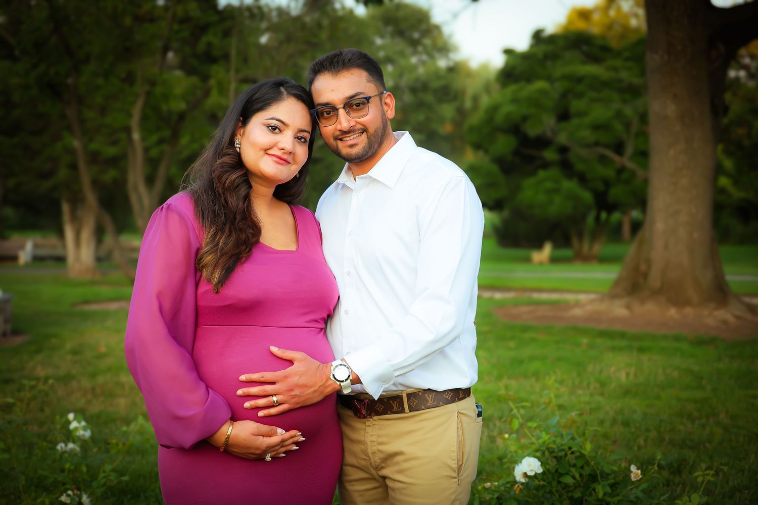 A couple shares romantic moments in a park setting during a sunny outdoor photo session.