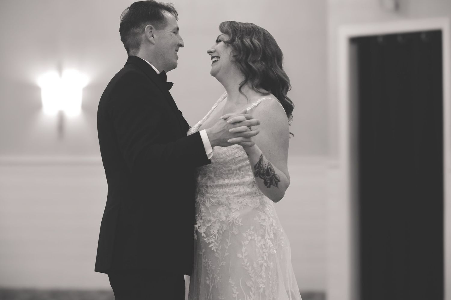 A couple shares their first dance at a wedding reception in black and white photography.