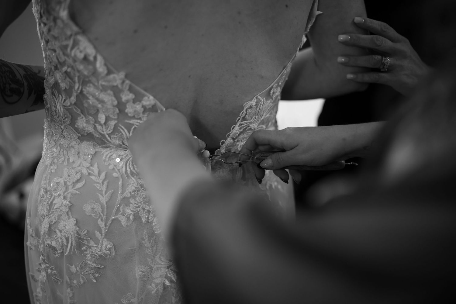 Black and white detail shots of a bride's lace wedding dress with intricate beading and embellishments.
