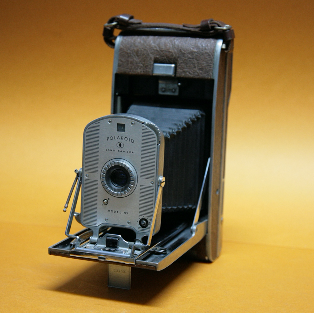 Vintage folding camera shown from multiple angles against amber backdrop, displaying its classic design and mechanisms.