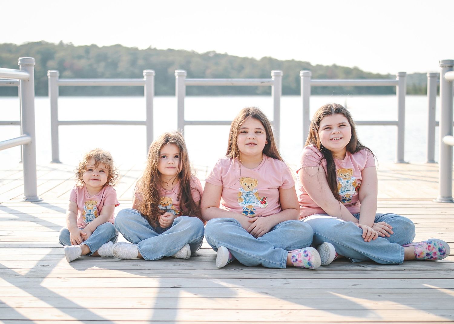 A group of people laying on a dock by the water wearing casual clothes and jeans.