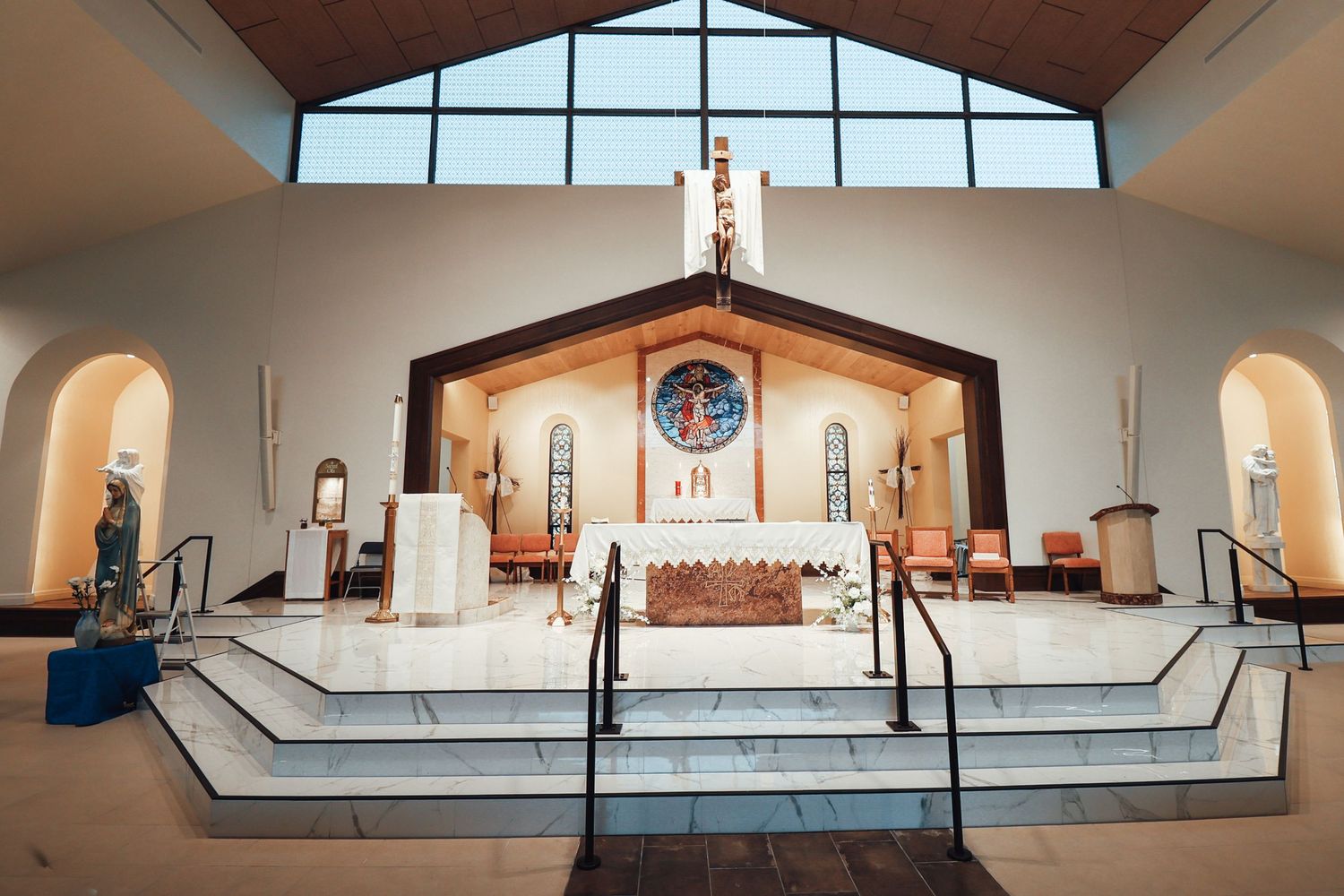 Modern church interior with vaulted ceiling, skylights, and minimalist design featuring white walls and wooden accents.