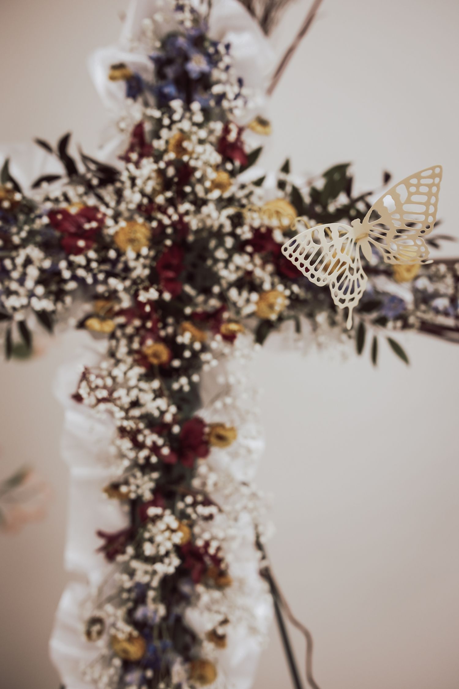 Delicate floral arrangement with burgundy and white flowers cascading against a soft neutral background.